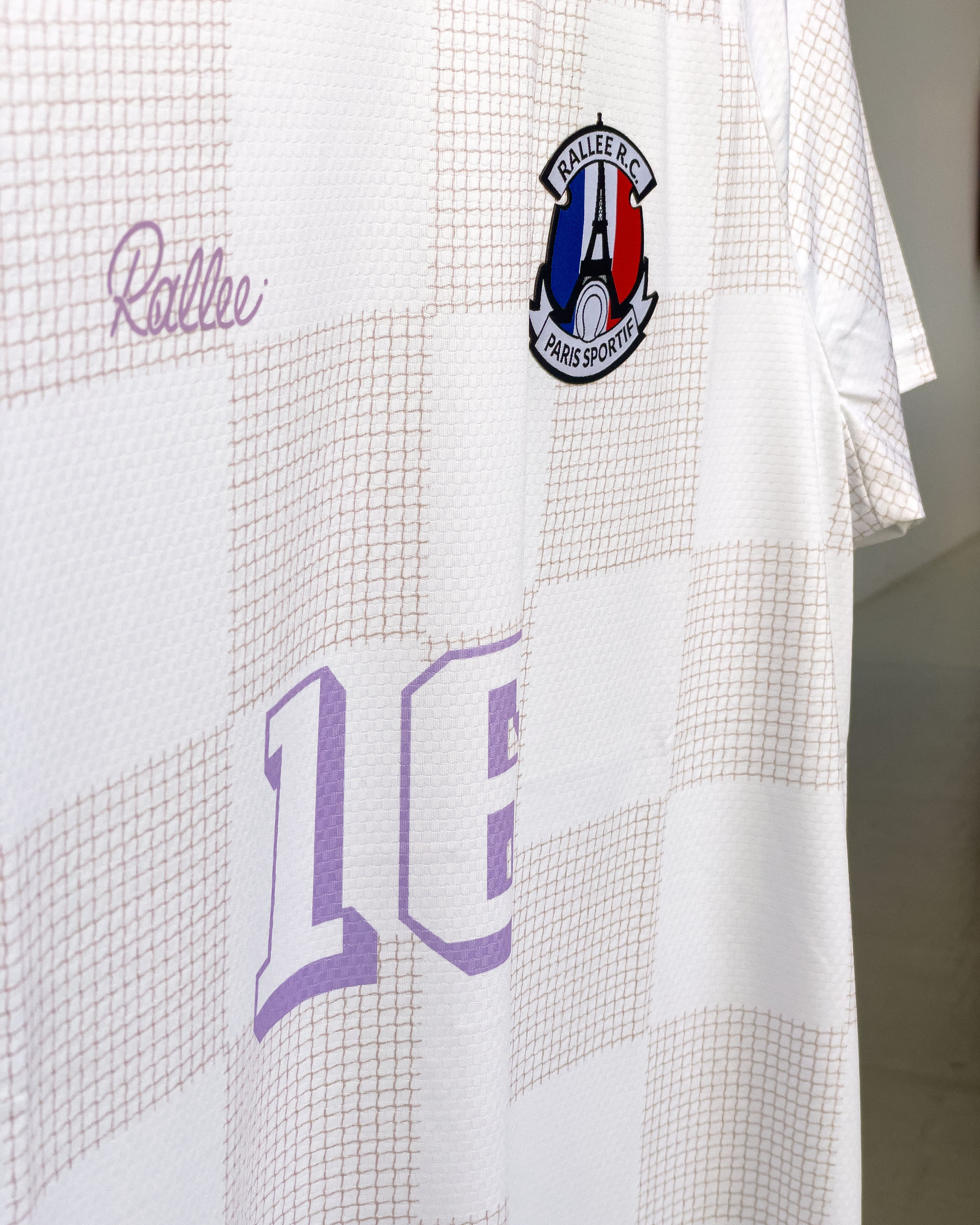 White sports jersey with purple text and a logo on a white background