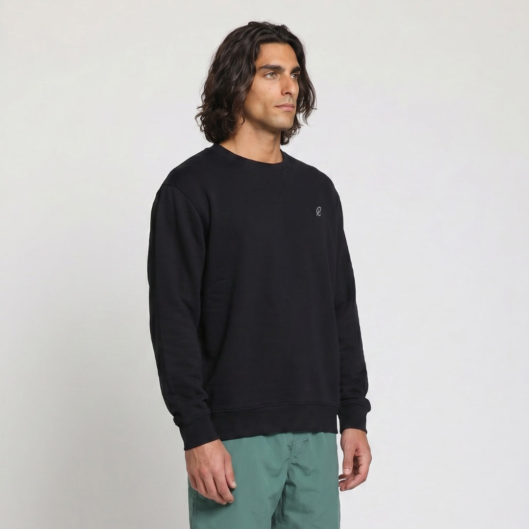 Man wearing a black sweatshirt with a small logo on a light gray background