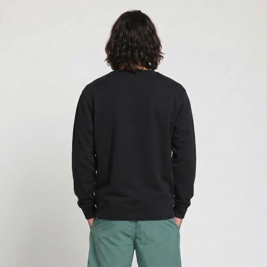 Person wearing a black sweatshirt and green pants against a plain background