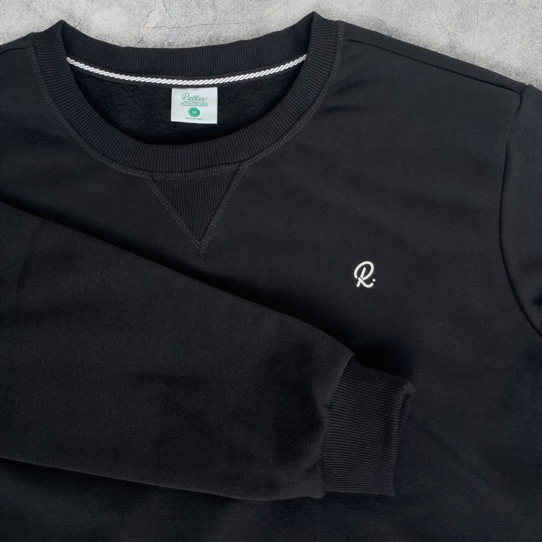 Black sweatshirt with a white logo on a gray surface