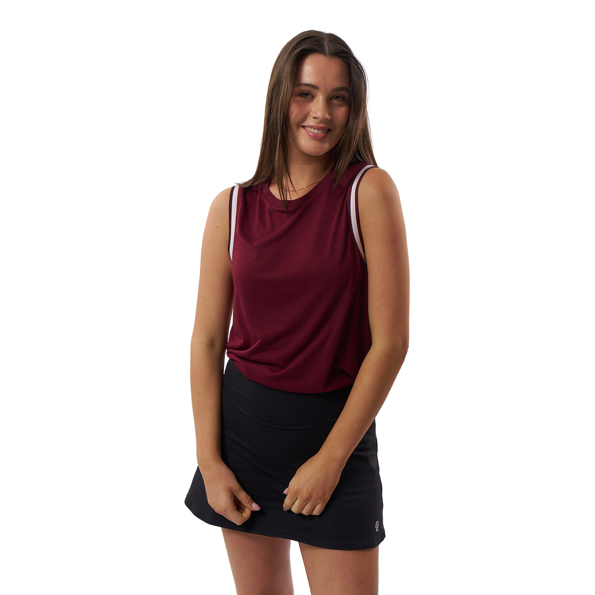 A woman modeling a sleeveless athletic tank top in deep burgundy with white shoulder trim, paired with a black tennis skirt, against a plain white background.