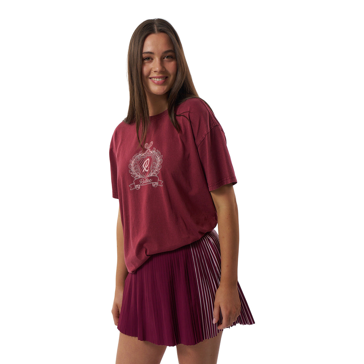 A young woman modeling a maroon short-sleeve graphic T-shirt and a matching pleated maroon tennis skirt against a plain white background.