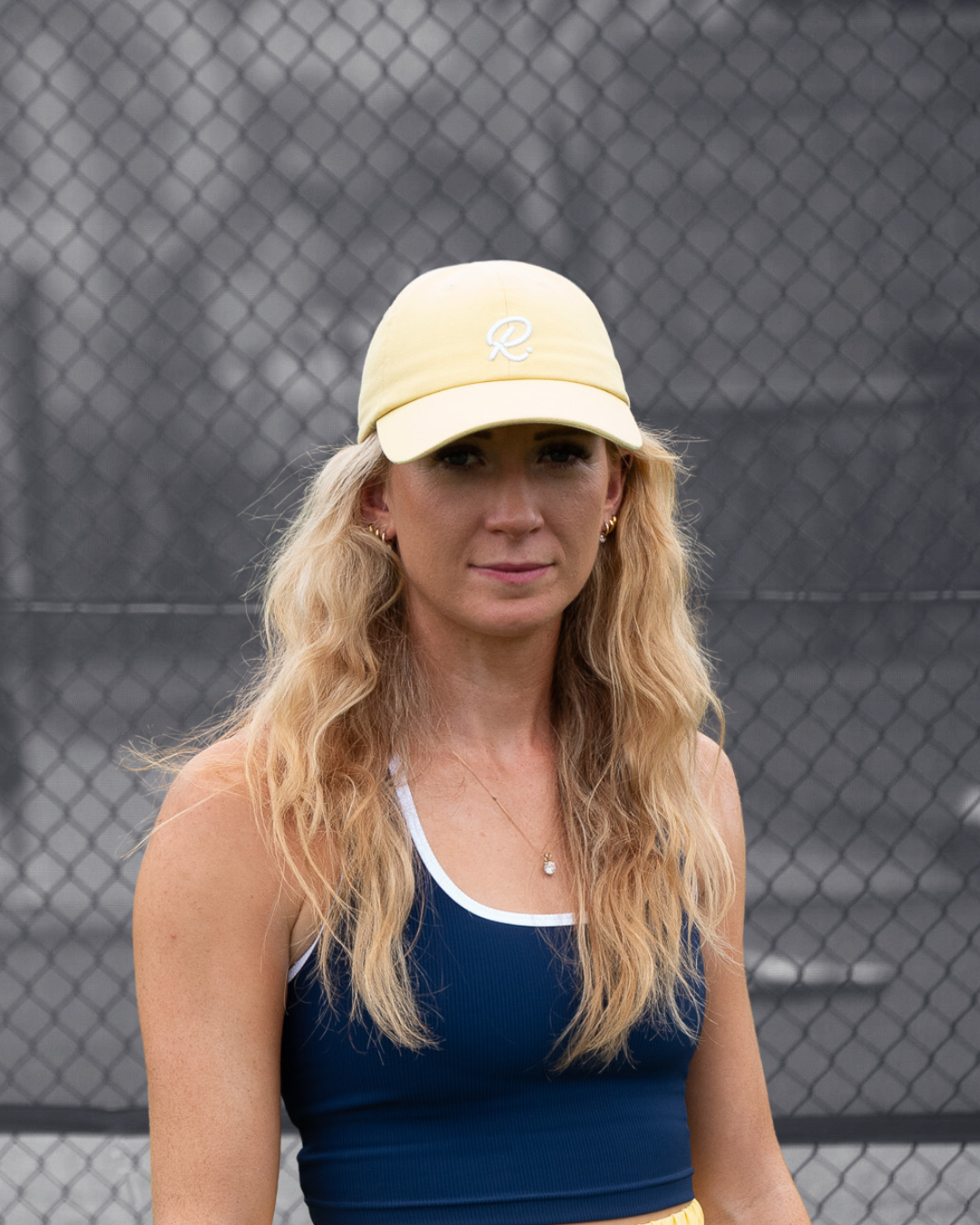 Woman wearing a yellow cap and blue top on a tennis court