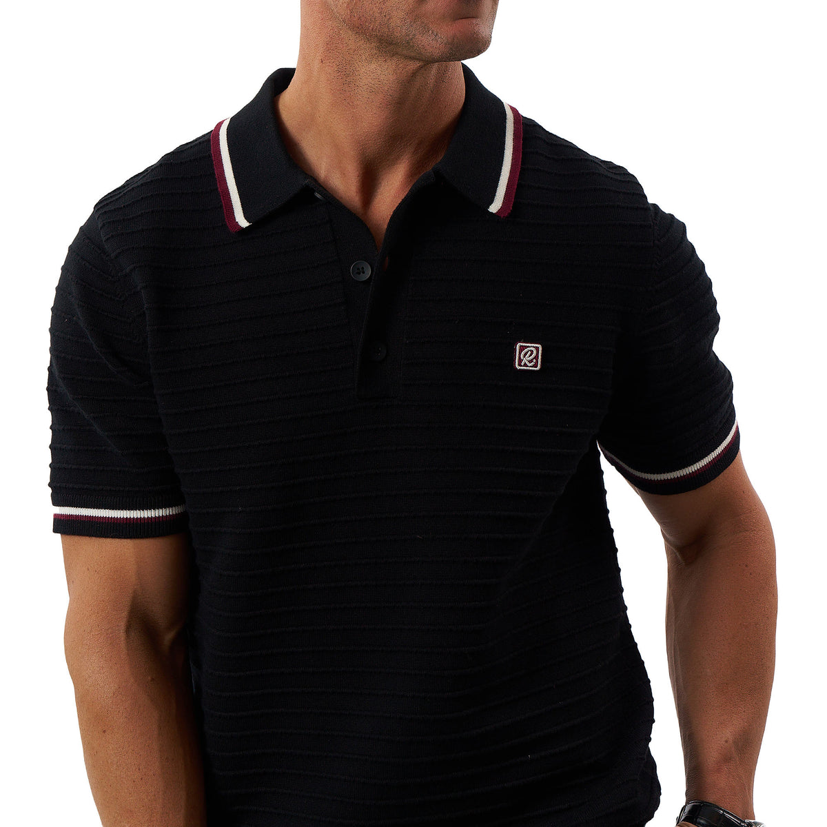 A man wearing a black ribbed short-sleeve polo shirt with a navy, white, and burgundy striped collar and sleeve cuffs, featuring a small embroidered "R" for Rallee logo on the left chest.
