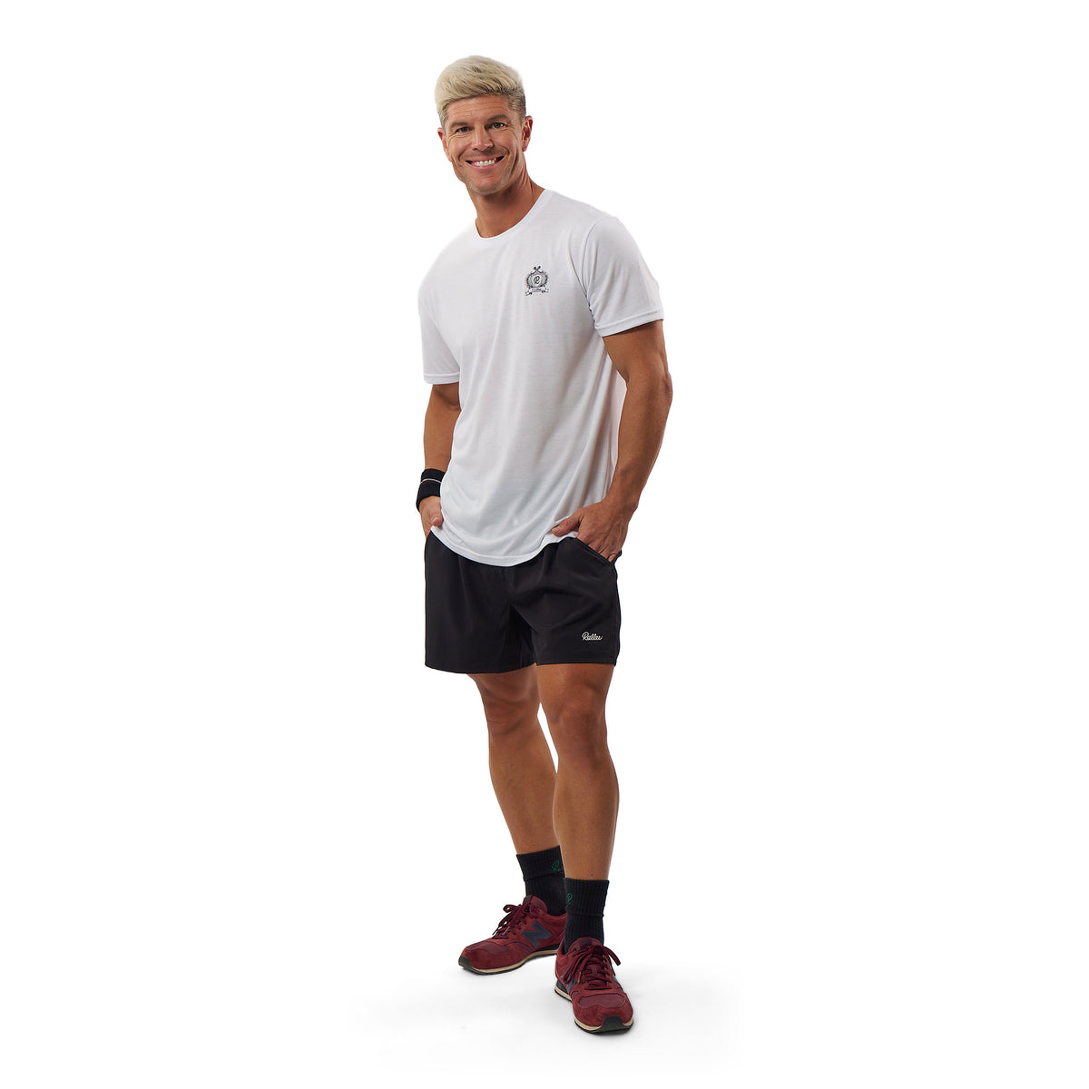 A man modeling athletic wear, featuring a white short-sleeve t-shirt with a small gray logo on the left chest and black athletic shorts, standing against a solid white background.