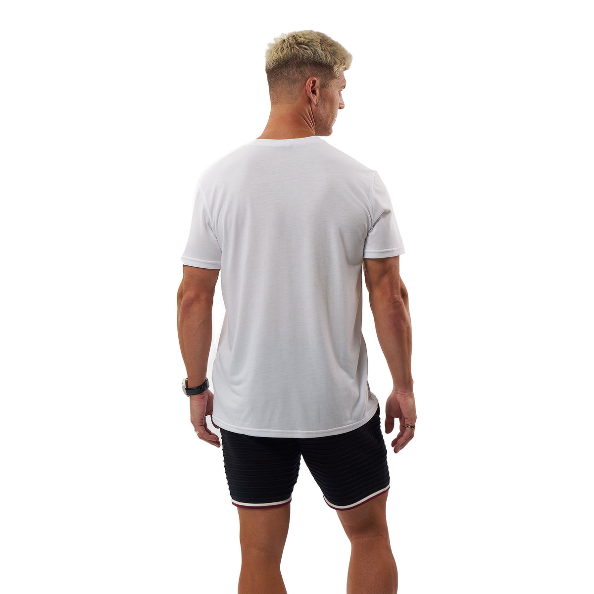 A man viewed from behind wearing a plain white short-sleeve t-shirt and black athletic shorts with a thin white stripe, set against a solid white background.