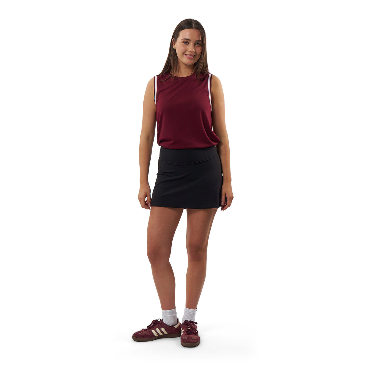 A model wearing a black athletic tank top, matching black shorts with a side tie, black socks, and black sneakers, standing against a solid white background.