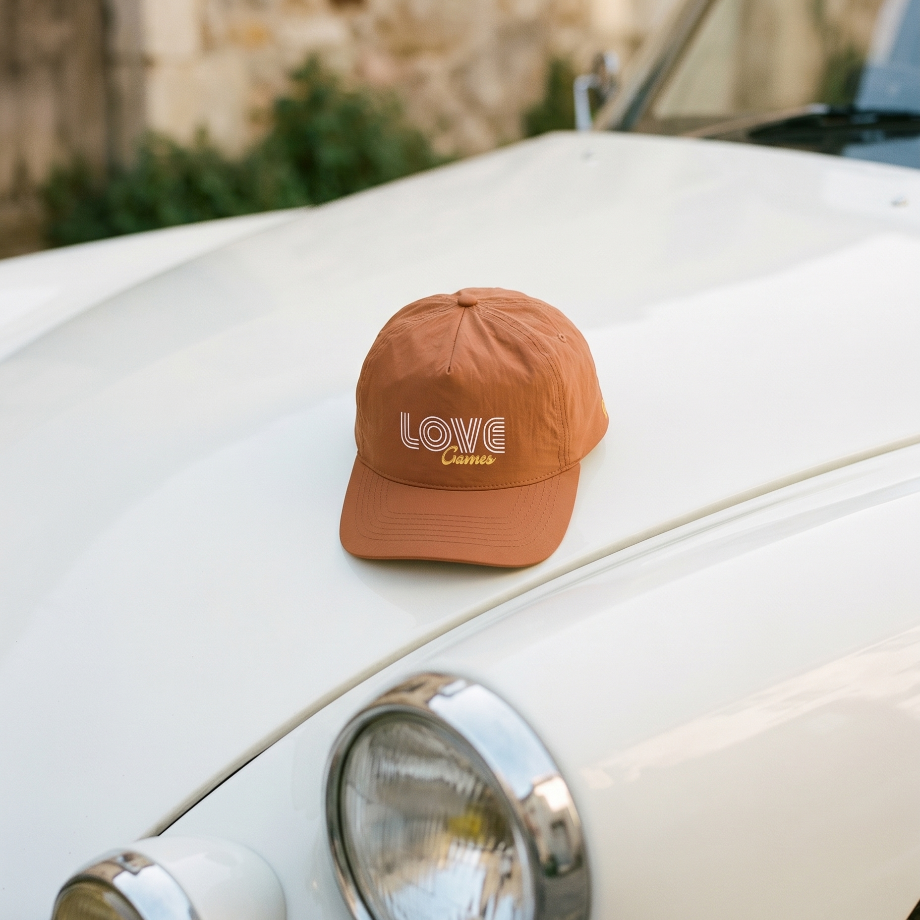 Clay coloured cap with 'LOVE Games' logo on a white car