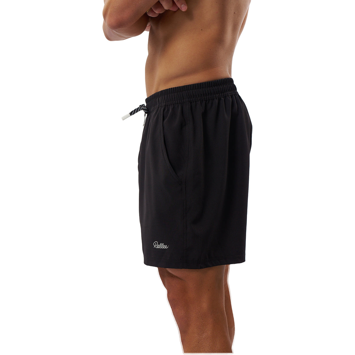 A side profile view of a man wearing black athletic shorts with a white drawstring and a small white embroidered logo near the hem, set against a plain white background.
